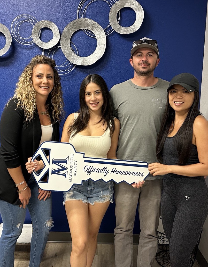 Alexis with three clients holding an "Officially Homeowners" key sign