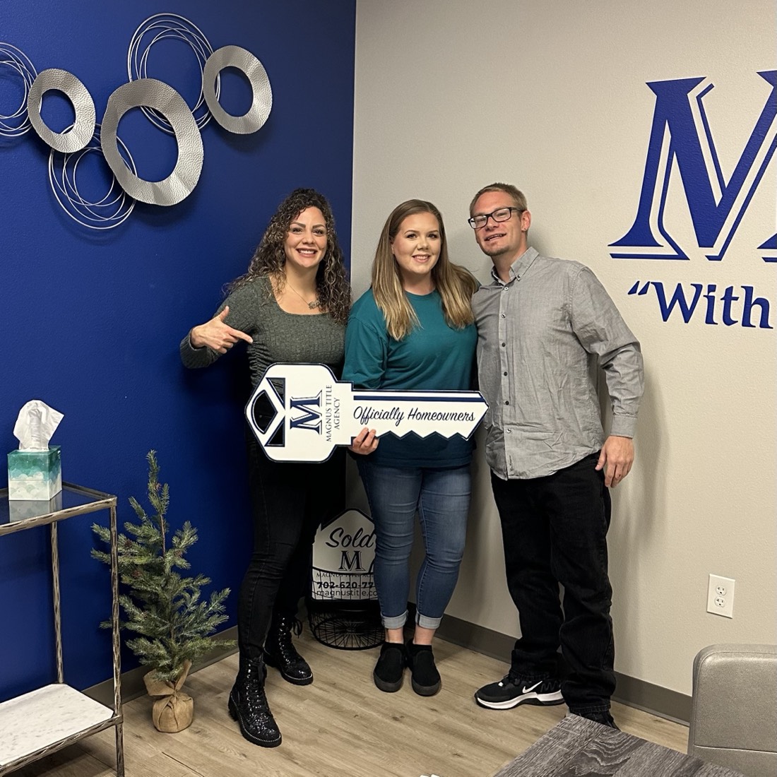 Alexis with a couple holding an "Officially Homeowners" key sign